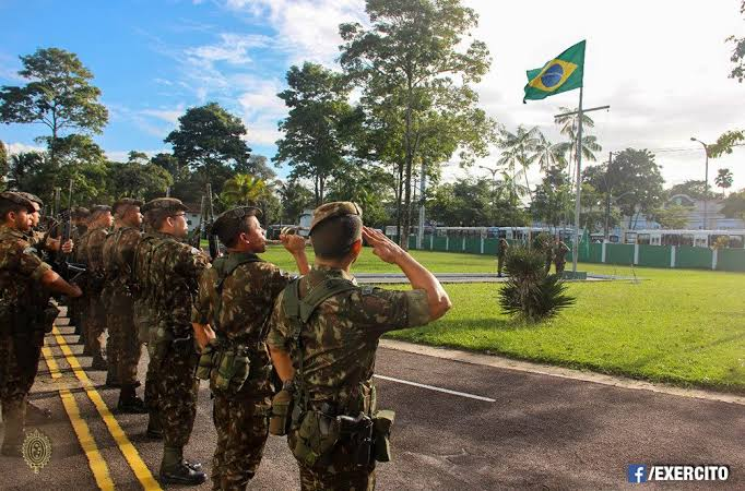 Militares em formação prestando continência à bandeira do Brasil